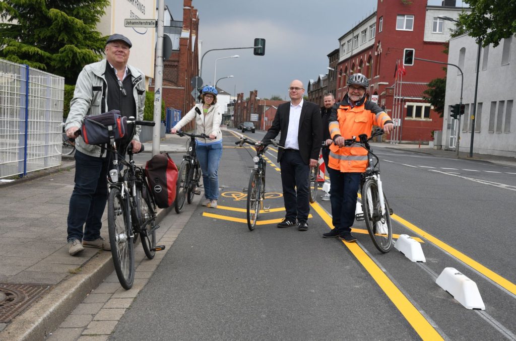 Mitarbeiter der Stadt stehen mit ihren Fahrrädern auf dem neuen Geschützten Fahrradstreifen