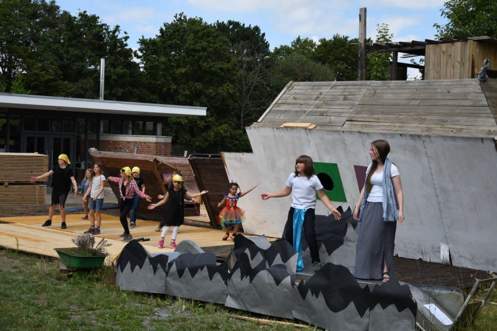 Eine Tanzszene aus dem Theaterstück vor dem großen Holzschff als Kulisse