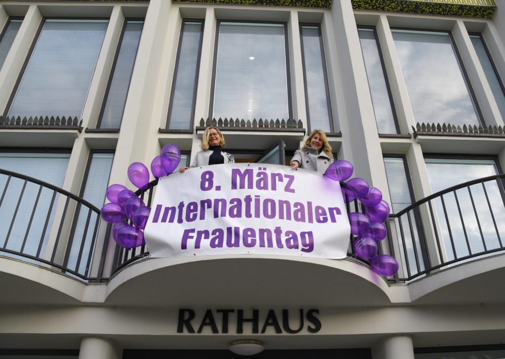 Die Gleichstellungsbeauftragte der Stadt Düren, Christina van Essen (re.), und Edith Wirthmann hissen zum Internationalen Frauentag das Banner am Rathaus.