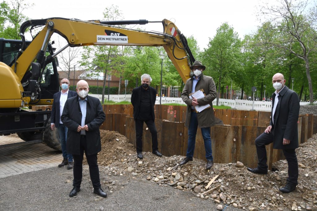 Gruppenfoto vor der Baustelle mit Bagger im Hintergrund