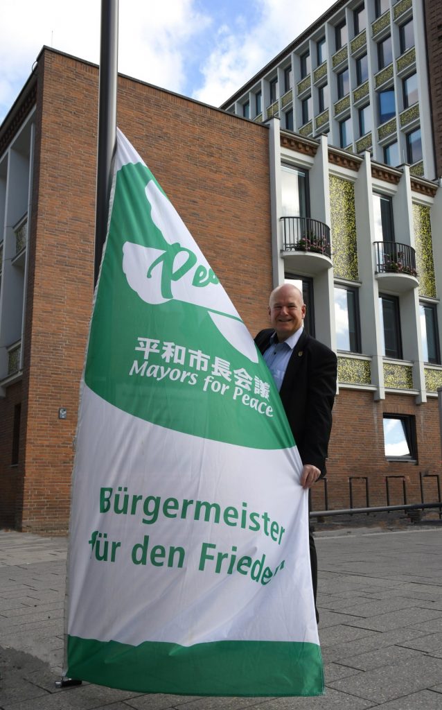 Bürgermeister Frank Peter Ullrich hisst heute symbolisch die Mayors-for-Peace-Flagge als Zeichen der Solidarität