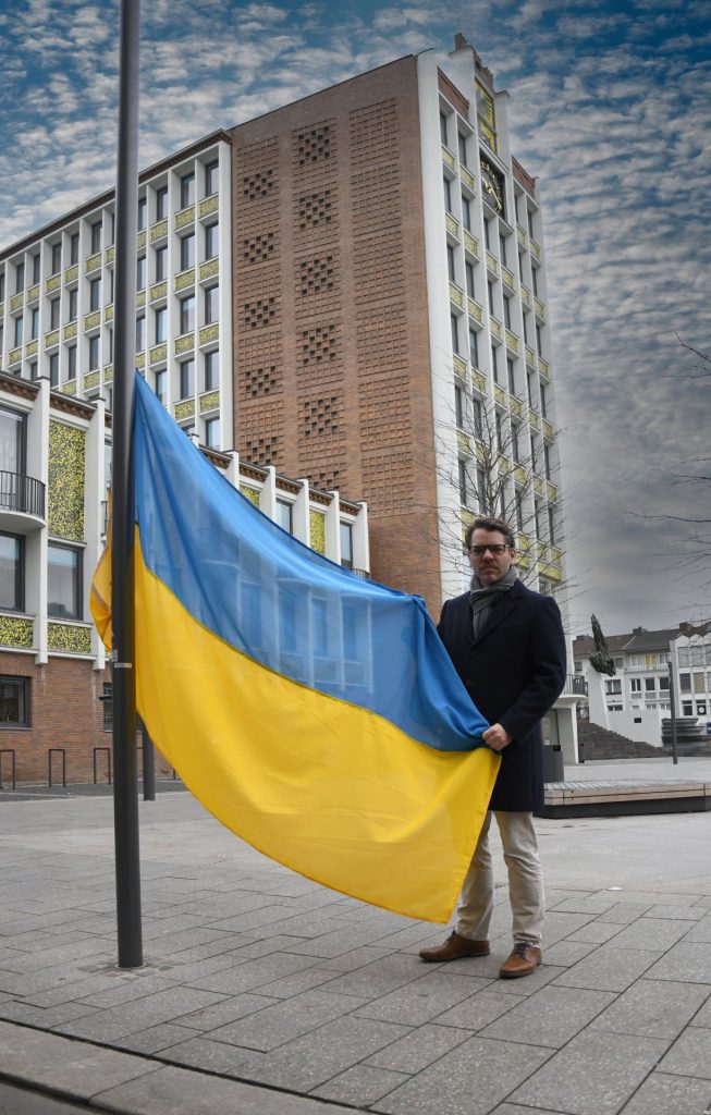 Dürens Erster Beigeordneter Thomas Hissel hisst vor dem Dürener Rathaus die ukrainische Flagge.