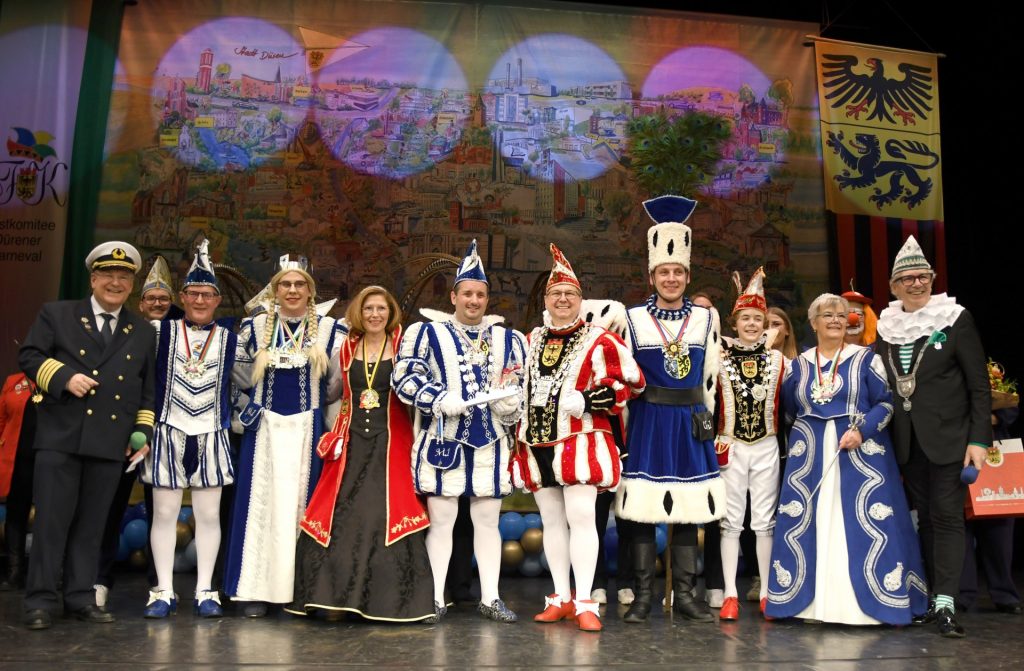 Zwei Prinzenpaare und ein Dreigestirn auf der Bühne, umrahmt von Bürgermeister Frank Peter Ullrich (li.) und dem Präsidenten des Festkomitees Dürener Karneval, Wino Ulhas (re.).
