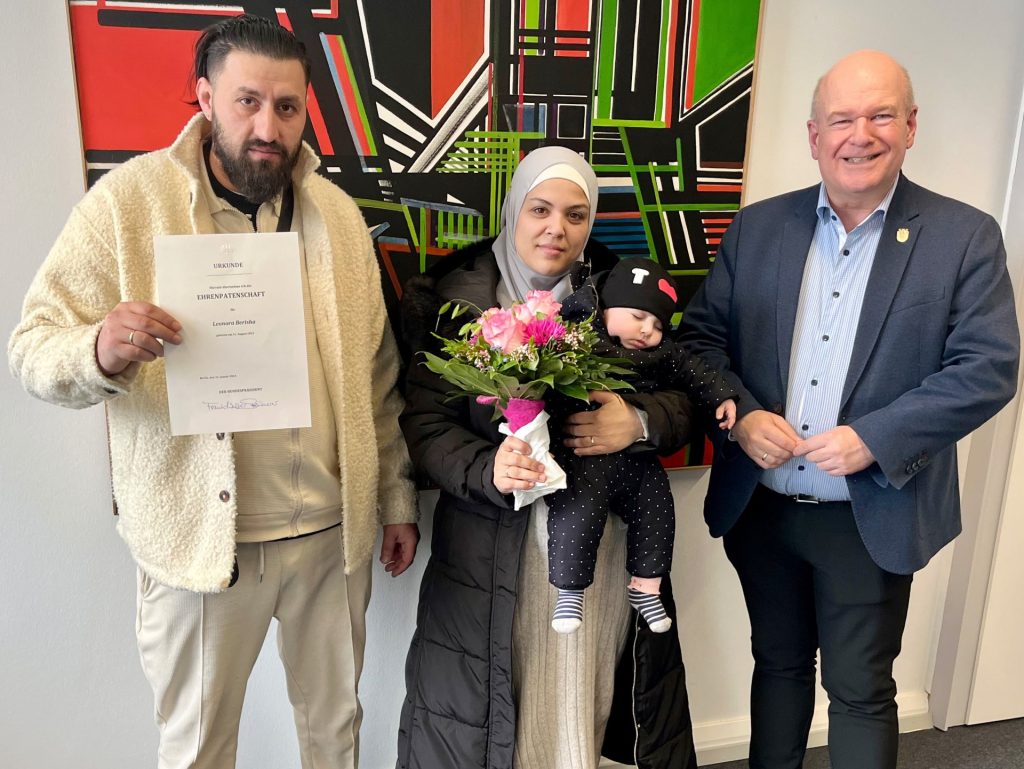 Im Rathaus hat Bürgermeister Frank Peter Ullrich (r.) die Urkunde für die Ehrenpatenschaft an Perparim (l.) und Johanna Berisha (Mitte) überreicht, die Bundespräsident Frank-Walter Steinmeier für deren siebtes Kind übernimmt. Leonora verschlief den großen