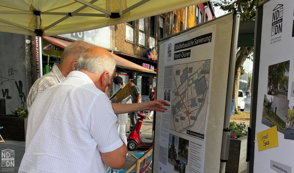 Zwei Menschen im Gespräch am Infostand der Sanierungsstelle