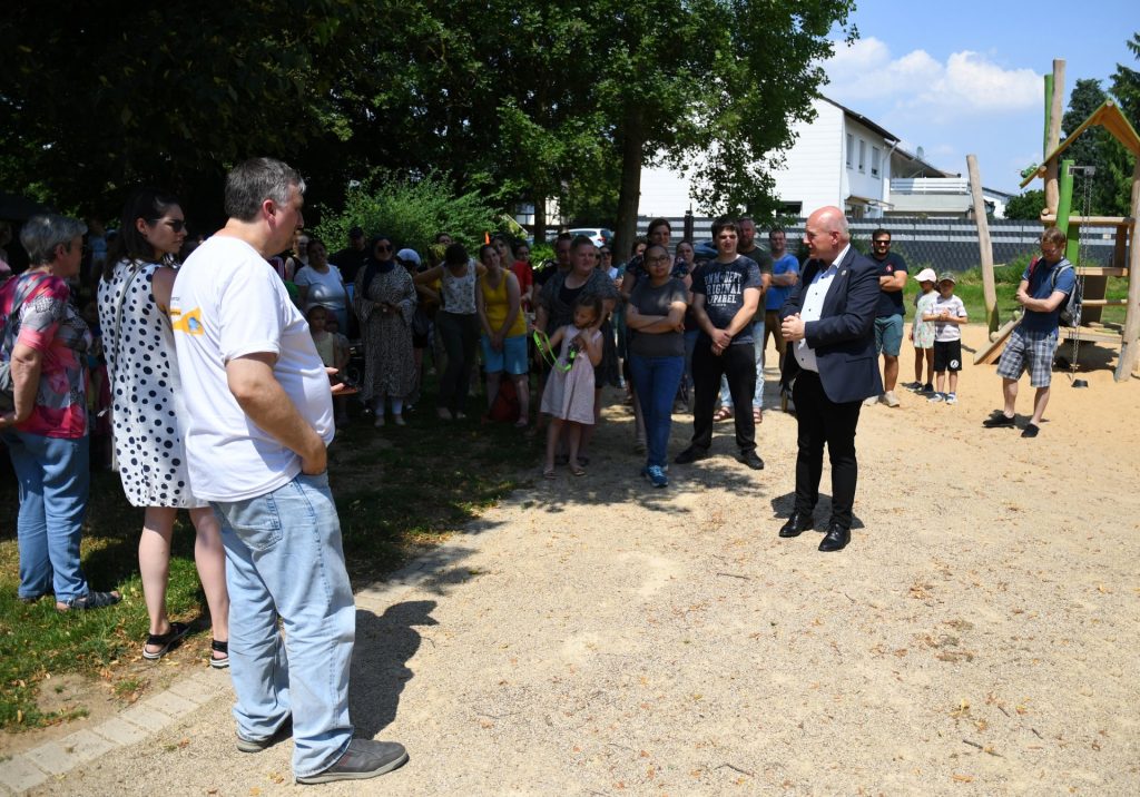 Das Foto zeigt Bürgermeister Frank Peter Ullrich bei der Freigabe des neu gestalteten Spielplatzes Möschengasse. Im Hintergrund Kinder