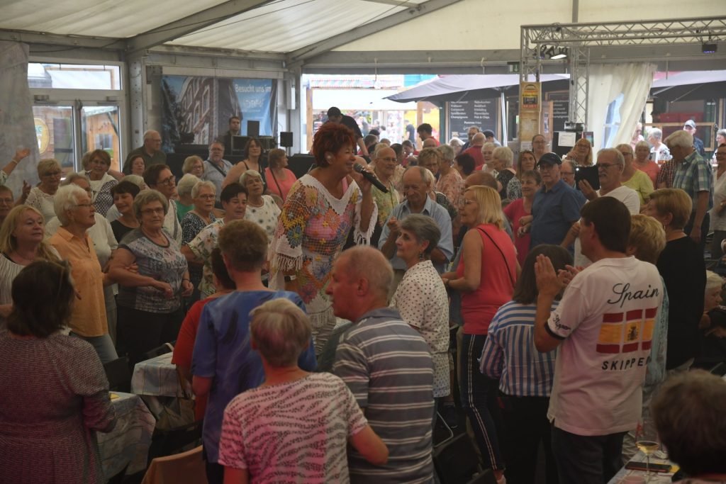 Das Foto zeigt Marita Köllner auf einem Tisch stehend, umgeben von ihren Fans.