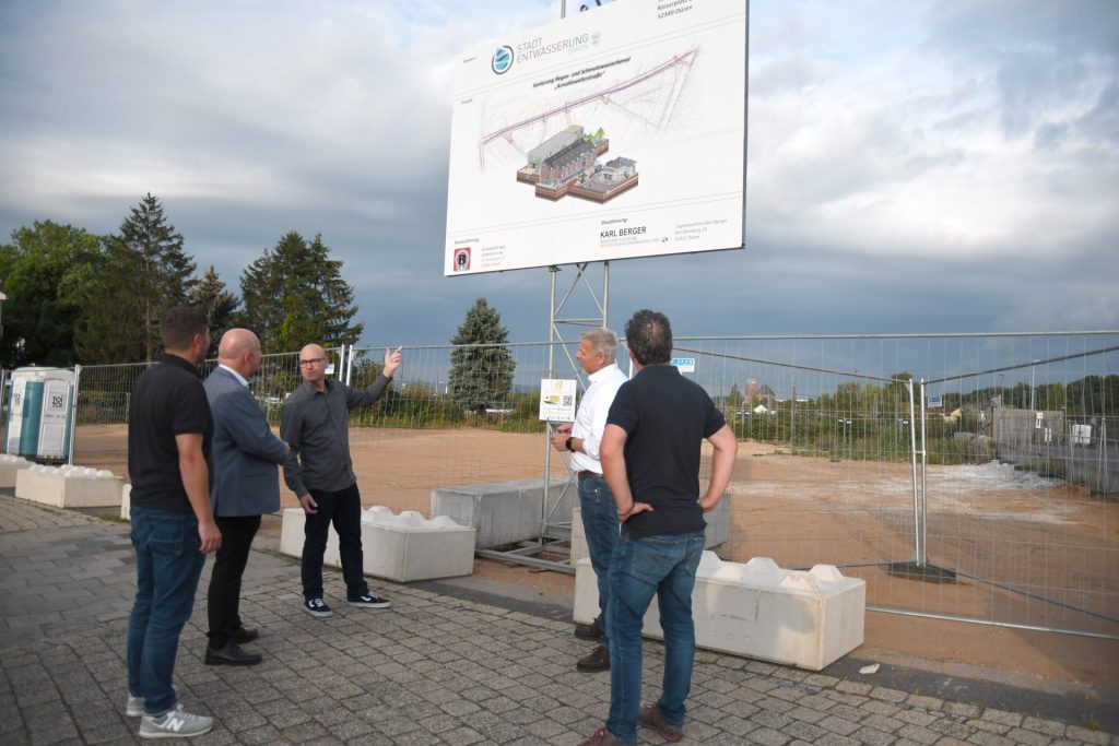 Die Gruppe steht vor einem Baustellenschild an der Baustelle in der Arnoldsweilerstraße.