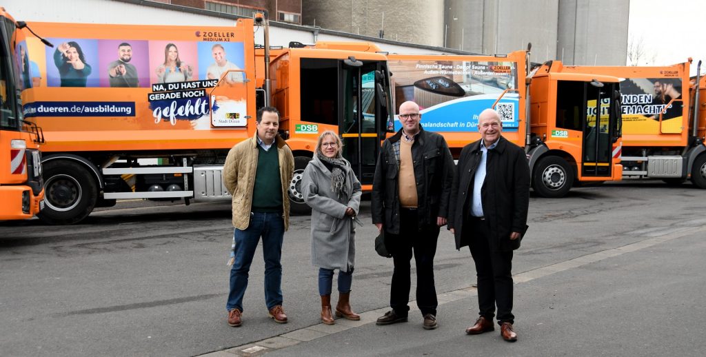 Menschengruppe vor Müllfahrzeugen