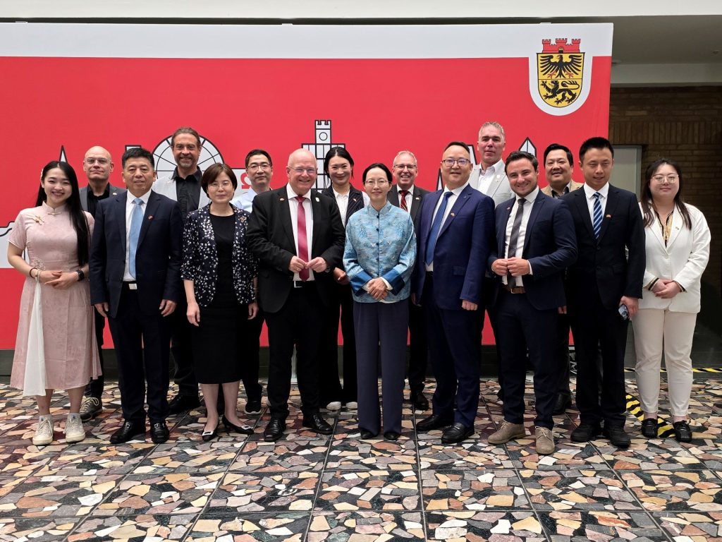 Gruppenfoto im Foyer des Dürener Rathauses. Im Hintergrund ist eine Leinwand mit der Skyline von Düren zu sehen.
