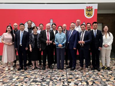 Gruppenfoto im Foyer des Dürener Rathauses. Im Hintergrund ist eine Leinwand mit der Skyline von Düren zu sehen.