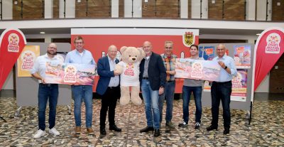 Gruppenfoto im Rathausfoyer mit einem Kirmes-Stoffbären in der Mitte.