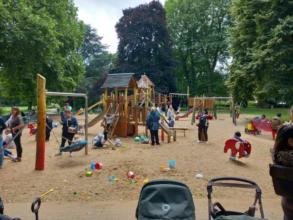 Das Foto zeigt Eltern und Kinder auf einem Spielplatz.