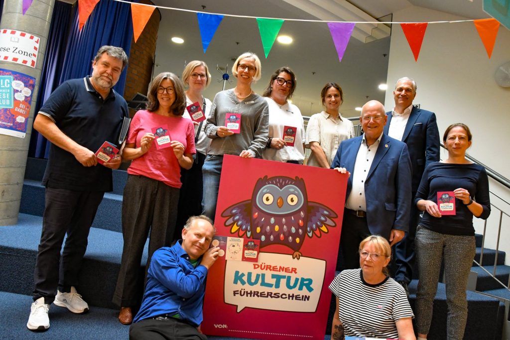 Gruppenfoto mit den Organisatoen und Bürgermeister Frank Peter Ullrich in der Stadtbücherei. Vorne ist das Logo, eine bunte Eule, zu sehen.