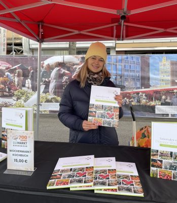 Das Foto zeigt Laura Göttgens, Mitarbeiterin der WIN.DN, die ein Exemplar des Kochbuches präsentiert. Kochbuch