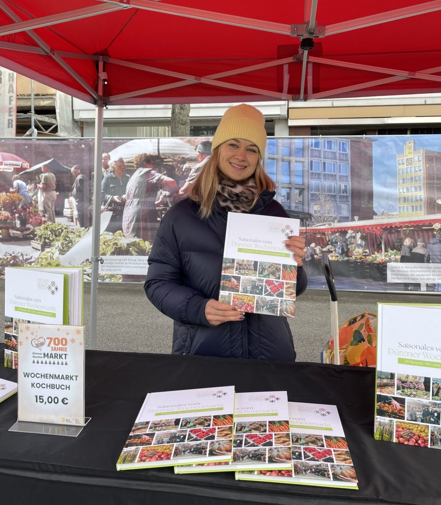 Das Foto zeigt Laura Göttgens, Mitarbeiterin der WIN.DN, die ein Exemplar des Kochbuches präsentiert. Kochbuch
