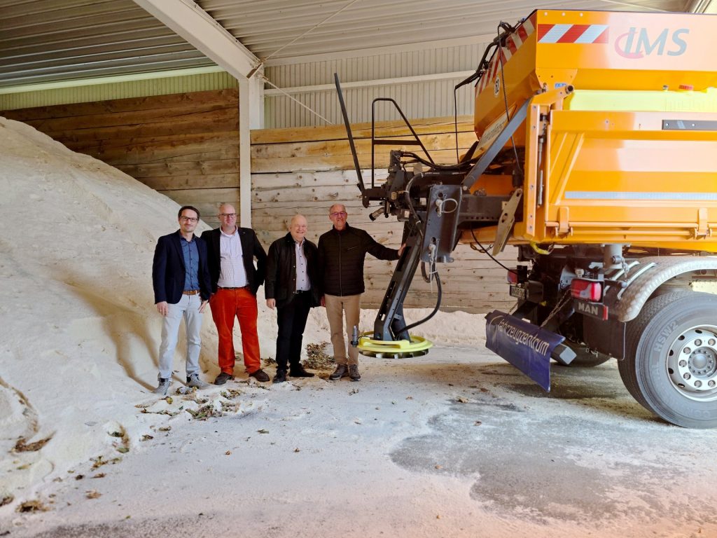 Gruppenbild mit Menschen neben einem Salzberg und einem Streufahrzeug