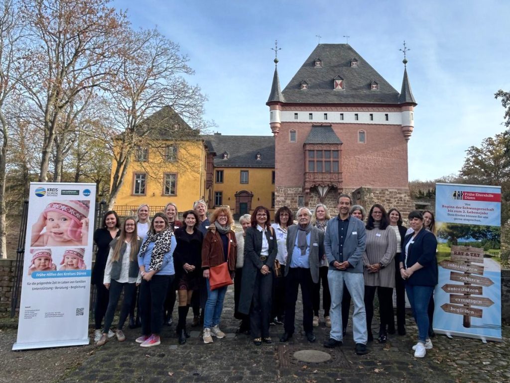 Menschen gucken zu einem Mann der auf der Bühne steht und einen Vortrag hält