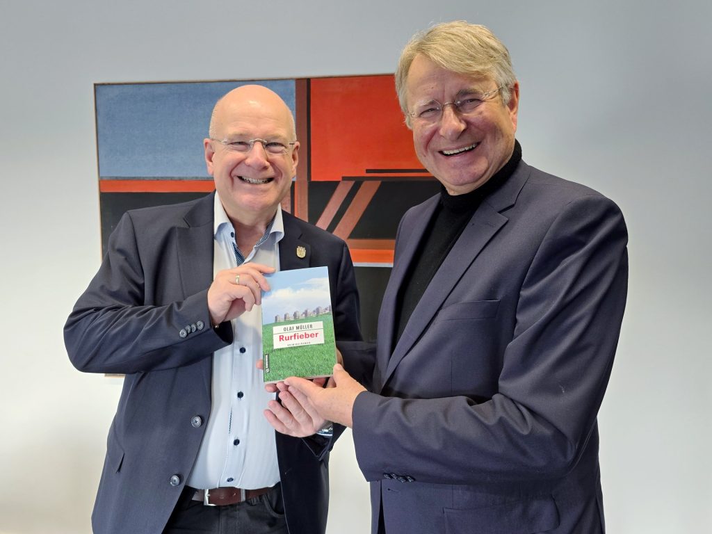 Zwei Männer stehen nebeneinander und halten zusammen ein Buch vor der Brust