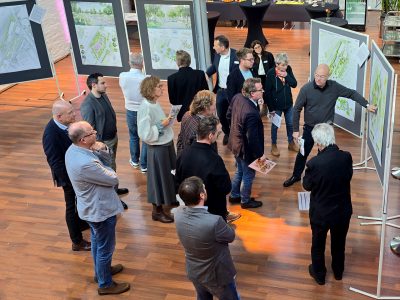 Mehrere Menschen stehen vor Stellwänden mit architektonischen Plänen