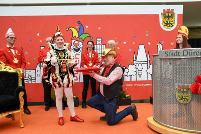 Schlüsselübergabe an den jüngsten Narrenherrscher Tom II. (Maaß). Bürgermeister Ullrich kniet und überreicht den Schlüssel.