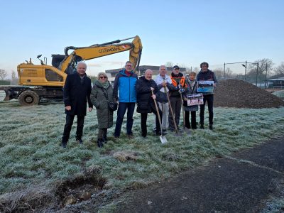 Gruppenbild mit Menschen vor einem Bagger