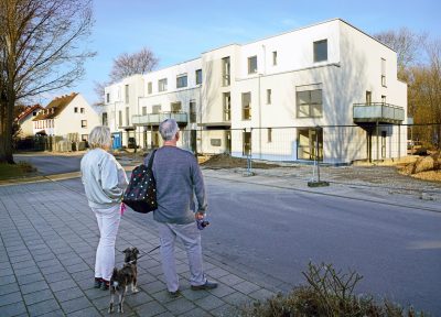 Zu sehen sind die Gebäude am Wehr, davor stehen Passanten.
