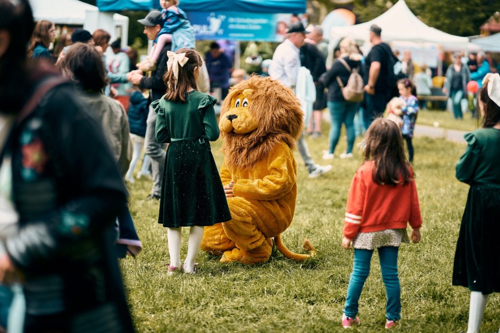 Menschen und ein Löwen-Maskottchen in einem Park
