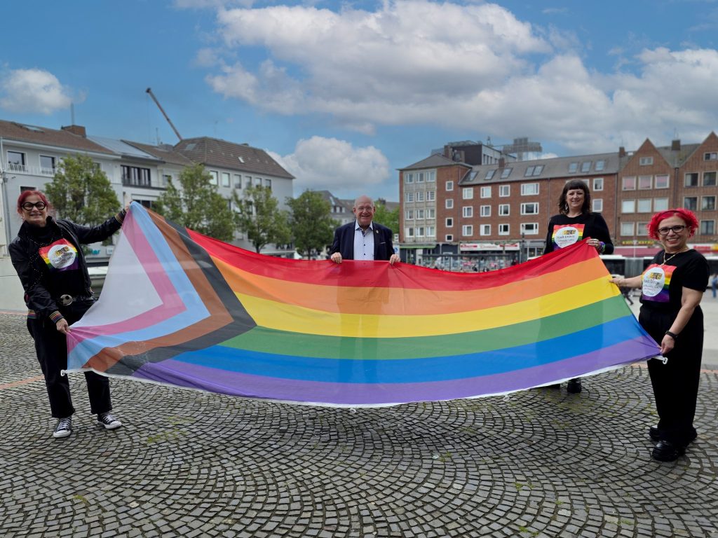 Gruppenbild mit Menschen und Regenbogenfahne