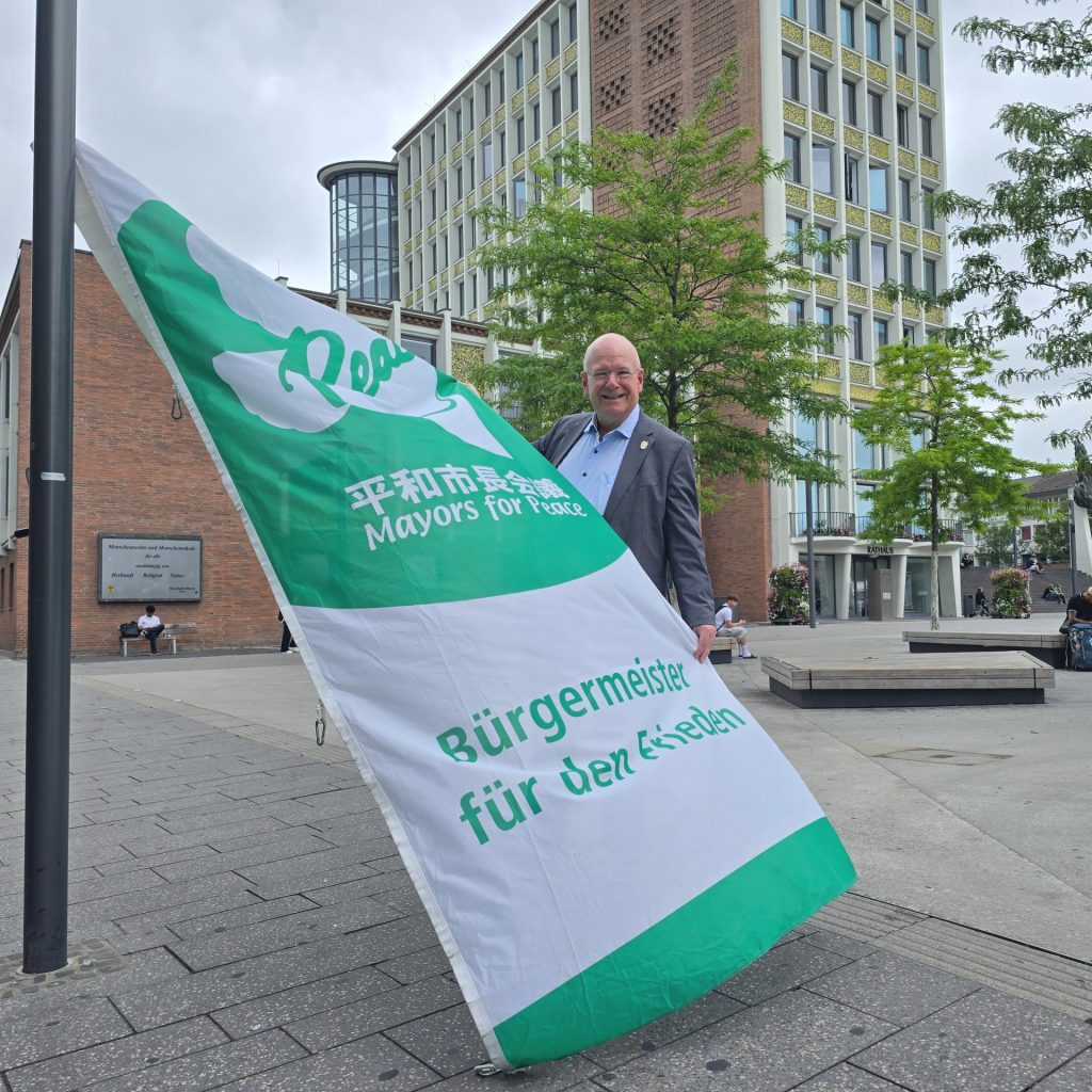 Ein Mann hisst eine Flagge an einem Fahnenmast