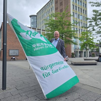 Ein Mann hisst eine Flagge an einem Fahnenmast