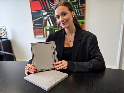 eine Frau sitzt an einem Tisch und zeigt ein Geschenkset in die Kamera