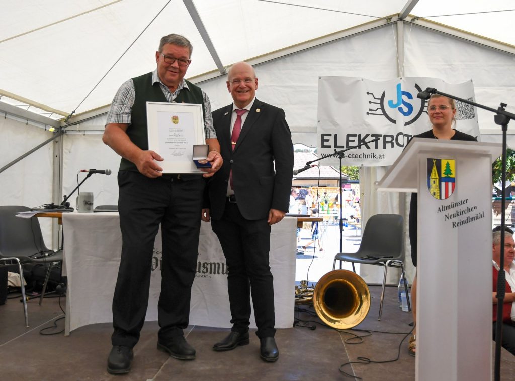 Das Foto zeigt Josef Moser, der die Urkunde und die Ehrenplakette präsentiert. rechts daneben steht Bürgermeister Frank Peter Ullrich.