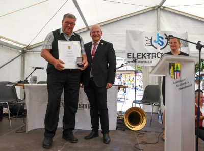 Das Foto zeigt Josef Moser, der die Urkunde und die Ehrenplakette präsentiert. rechts daneben steht Bürgermeister Frank Peter Ullrich.