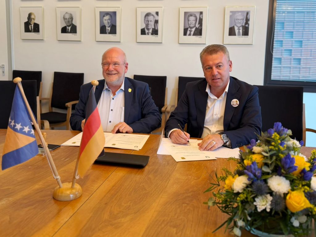 Zwei Männer sitzen an einem Tisch und unterschreiben ein Dokument